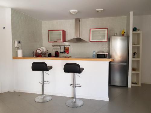 eine Küche mit zwei Barhockern und einem Kühlschrank in der Unterkunft Residencial Los Martines in El Médano