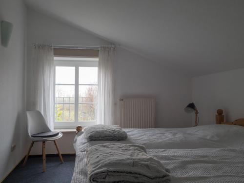 a bedroom with a bed and a chair and a window at Ferienwohnung-Himmelblau-auf-dem-Ferien-Bauernhof-Nielson-in-Bisdorf-in-Inselmitte in Bisdorf