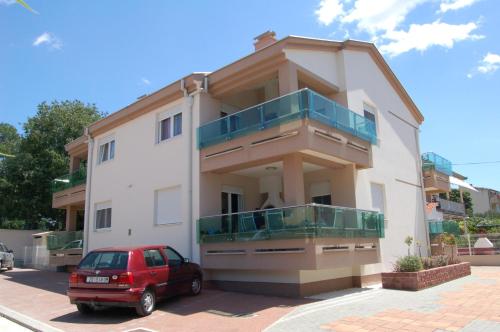 a building with a red car parked in front of it at Apartmani FAMILY in Sveti Filip i Jakov
