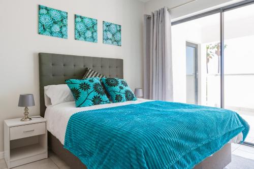 a bedroom with a bed with blue sheets and a window at Alimama Spaces: Vik Whisken in Midrand