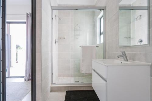 a white bathroom with a shower and a sink at Alimama Spaces: Vik Whisken in Midrand