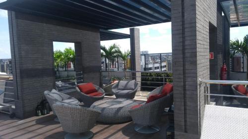 un patio con sillas y mesas en un balcón en Apartamento de luxo no coração da ponta verde, en Maceió