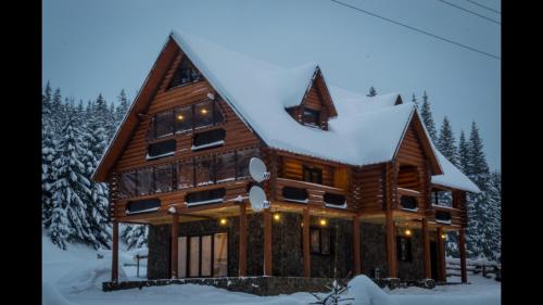a large wooden house with snow on the roof at Маєток горгани in Synevyrsʼka Polyana