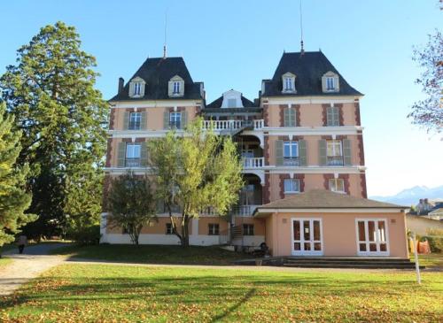 un grand bâtiment rose avec une grande cour dans l'établissement VILLA BONVOULOIR, à Bagnères-de-Bigorre