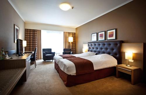 um quarto de hotel com uma cama, uma secretária e uma televisão em Hyllit Hotel em Antuérpia