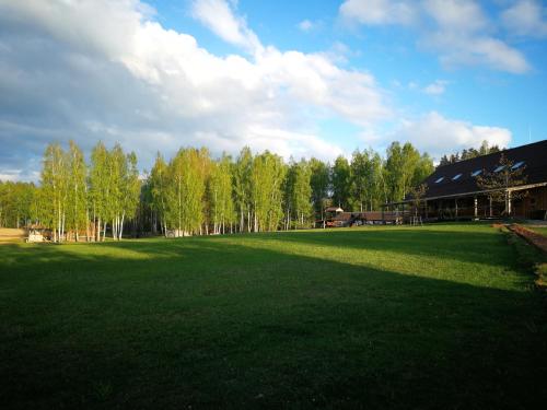 a large green field with trees and a building at Sodyba Vieversynė in Duokiškis