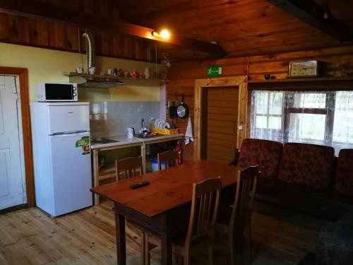 a kitchen with a wooden table and a white refrigerator at Sodyba Vieversynė in Duokiškis