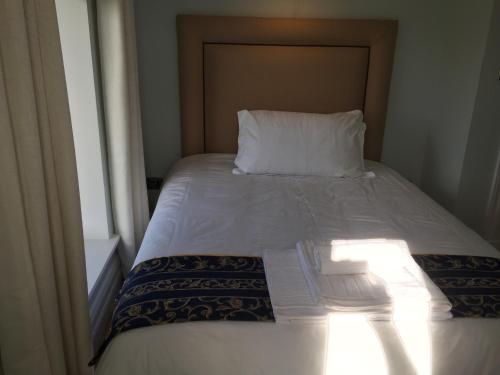 a bed with a white pillow and a window at Farmhouse Boutique in Ballyheigue