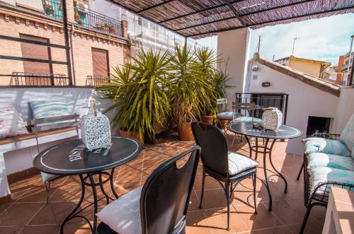 2 mesas y sillas en un balcón con plantas en tuGuest Gran Vía Apartments, en Granada