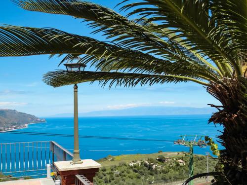 uma vista para o oceano a partir de uma varanda com uma palmeira em Villa Athèna em Taormina