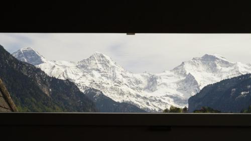 a view of a snow covered mountain range from a window at Adventure Hostel Interlaken in Interlaken