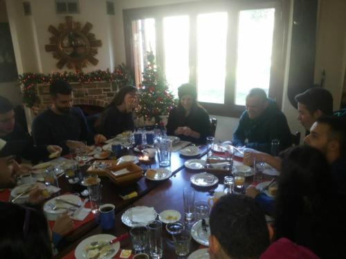 a group of people sitting around a table in front of a christmas tree at Menelaos Apartments in Lefokastro