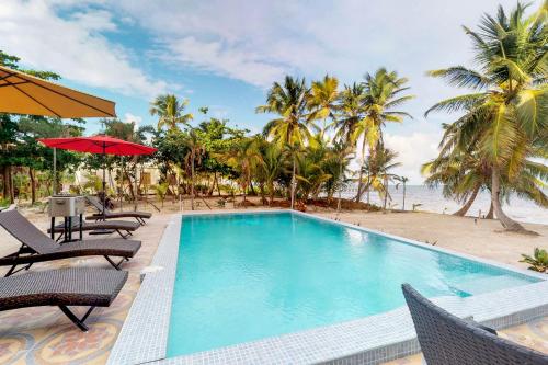 a swimming pool next to a beach with palm trees at Blue Water Beach Villas in San Pedro