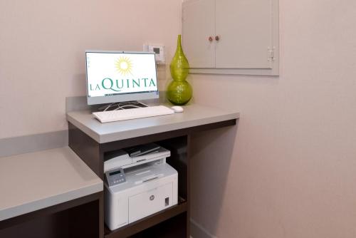 a desk with a computer and a vase on it at La Quinta by Wyndham Indianapolis South in Indianapolis