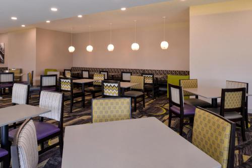 a dining room with tables and chairs and lights at La Quinta by Wyndham Indianapolis South in Indianapolis