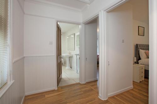 a hallway with a bathroom with a sink and a mirror at Victoria’s Place in Chelmsford