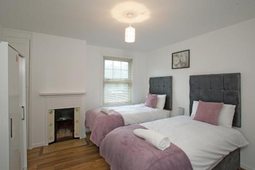 een slaapkamer met 2 bedden en een open haard bij Victoria’s Place in Chelmsford