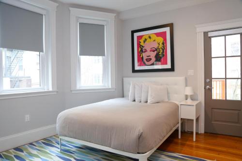 a white bedroom with a bed and a table and windows at A Stylish Stay w/ a Queen Bed, Heated Floors.. #23 in Brookline