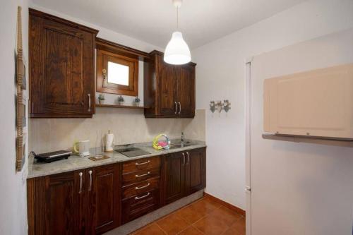 a kitchen with wooden cabinets and a white wall at Buda in Tinajo