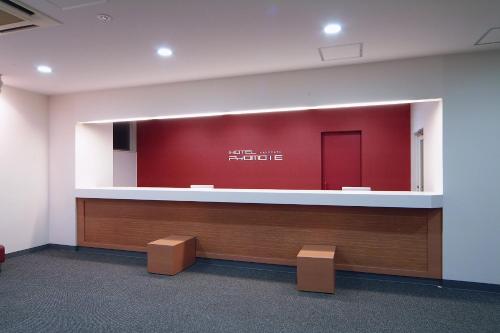 an empty waiting room with a red wall and a counter at Hotel Promote Hakodate in Hakodate