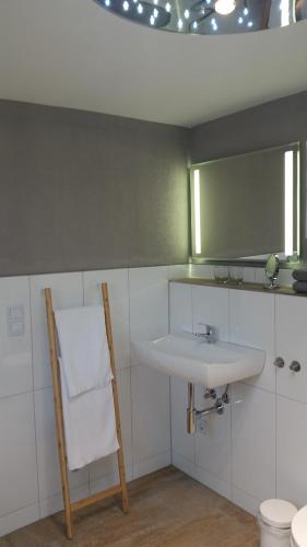 La salle de bains est pourvue d'un lavabo, d'un miroir et d'une chaise. dans l'établissement Ferienwohnung Hirmer, à Zirndorf