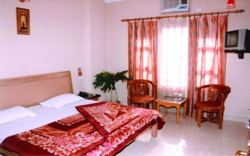 a bedroom with a bed and chairs and a window at Hotel King in Haridwār