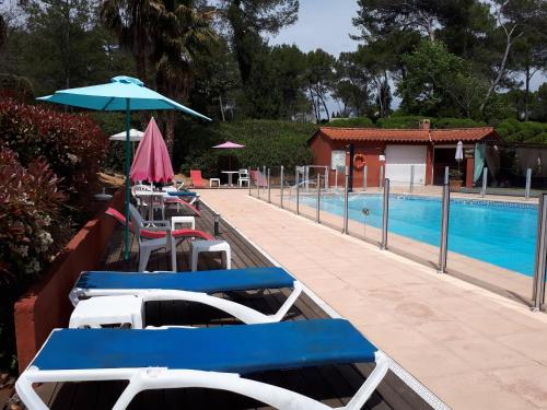 - deux chaises longues et un parasol à côté de la piscine dans l'établissement Apparthotel proche de Cannes, à Mouans-Sartoux