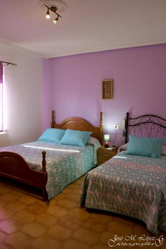 a bedroom with two beds and a purple wall at Hostal Restaurante El Final in El Cabaco