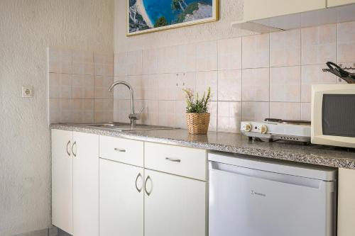 a kitchen with white cabinets and a sink and a microwave at Panorama Fanari studios and apartments in Argostoli