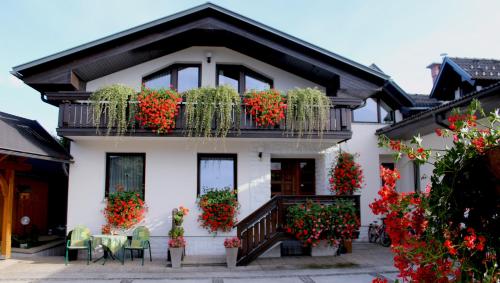 une maison blanche avec des fleurs sur le balcon dans l'établissement Garden Apartments Janša, à Radovljica