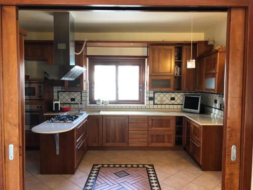 a large kitchen with wooden cabinets and a window at Casa di Antonello in Cosenza