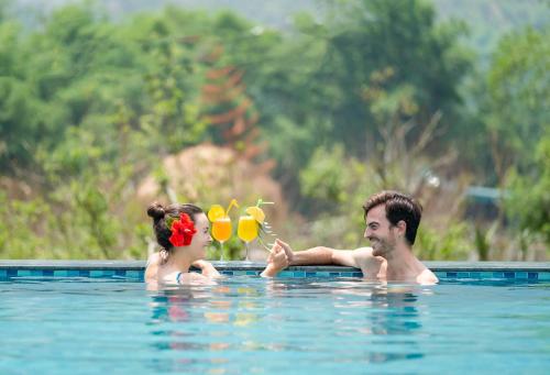 a man and a woman in a swimming pool at Mai Chau Mountain View Resort in Mai Chau