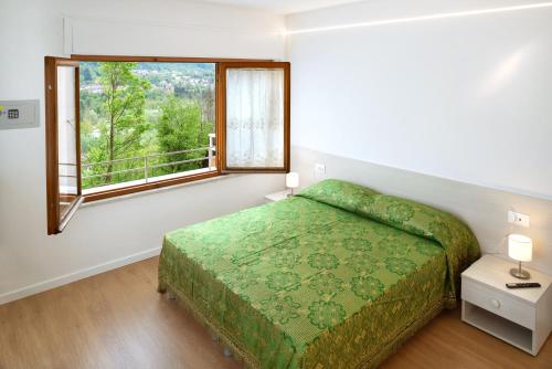 Un dormitorio con una cama verde y una ventana en Dolomiti Suite en Belluno