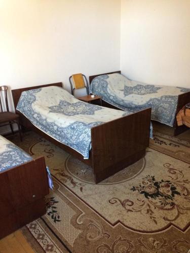 a room with three beds and chairs and a rug at Huseyn Houses in Ganja