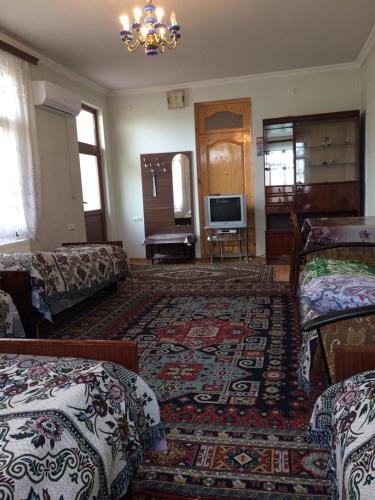 a living room with two beds and a television at Huseyn Houses in Ganja