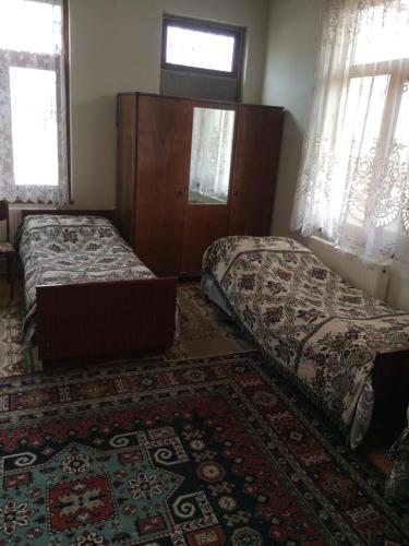 a bedroom with two beds and a rug at Huseyn Houses in Ganja
