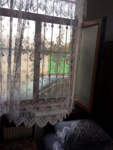 a window with a curtain and a bed in a room at Huseyn Houses in Ganja