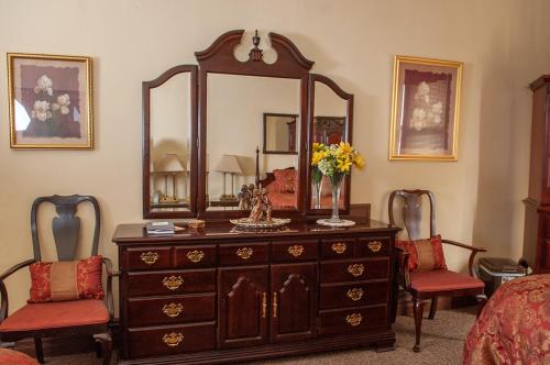 a bedroom with a dresser with a mirror and two chairs at The Historic Wolf Hotel in Ellinwood