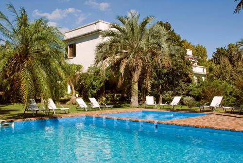 una piscina di fronte a una casa con palme di Hotel Villa Victoria de Tigre a Tigre