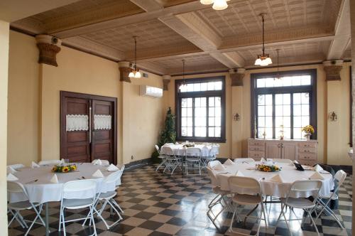 a room with white tables and chairs and windows at The Historic Wolf Hotel in Ellinwood