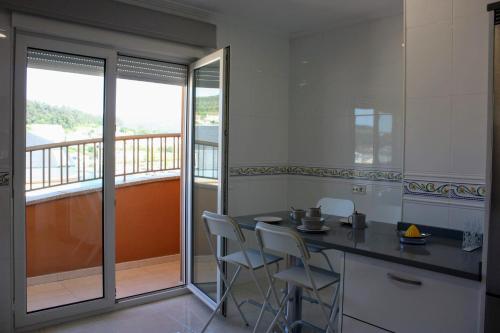 eine Küche mit einem Tisch und Stühlen sowie einen Balkon in der Unterkunft Apartamento en Cee con vistas al mar in Cee