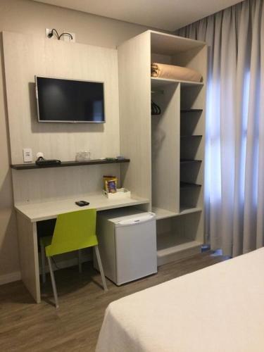 a room with a desk and a tv on a wall at Scarpelli Palace Hotel in Sorocaba