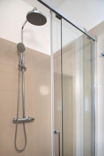 a shower with a glass door and a shower head at Dolomiti Suite in Belluno