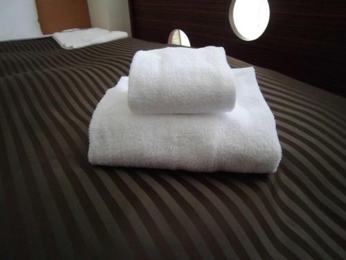 two towels are stacked on top of a bed at Hotel Promote Hakodate in Hakodate
