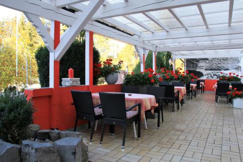 un patio con mesas y sillas bajo una pérgola blanca en Historisches Landhotel Studentenmuehle, en Nomborn