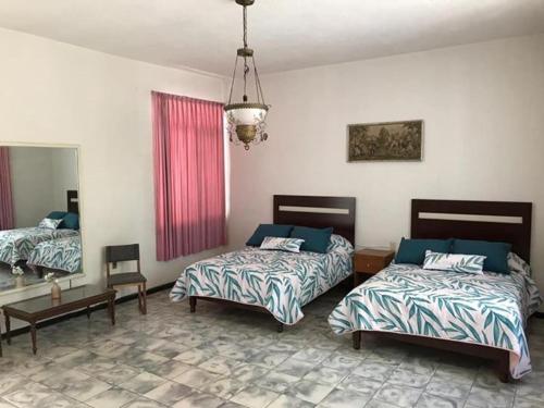 - une chambre avec 2 lits et un lustre dans l'établissement Antigua Casa de la Alameda, à Aguascalientes