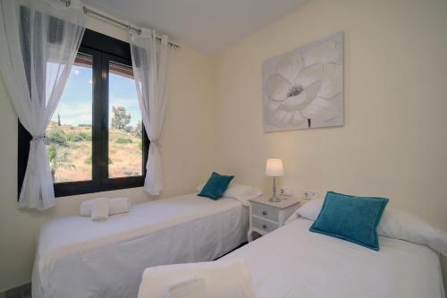 two beds in a room with a window at Apartamento Costa Galera DUPLEX PENTHOUSE in Estepona