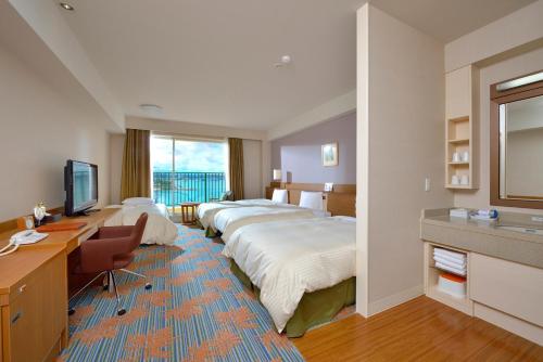 a hotel room with three beds and a desk at Vessel Hotel Campana Okinawa in Chatan