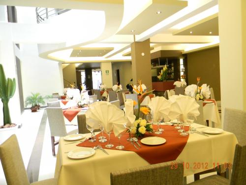 un comedor con una mesa con manteles y flores blancas en Miculla Hotel, en Tacna