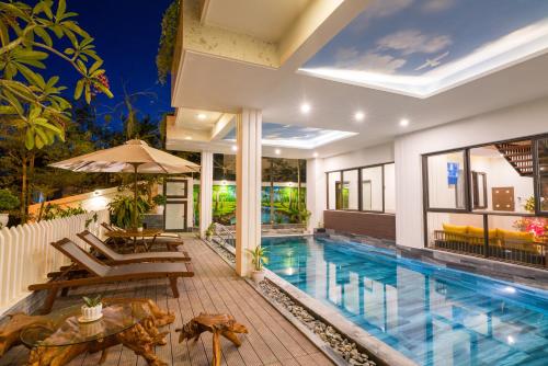 a swimming pool in a villa with a patio and a house at Hoi An Grace River Villa in Hoi An